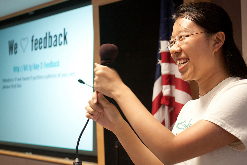 Sisi Wei smiling in front of a Code with me presentation.