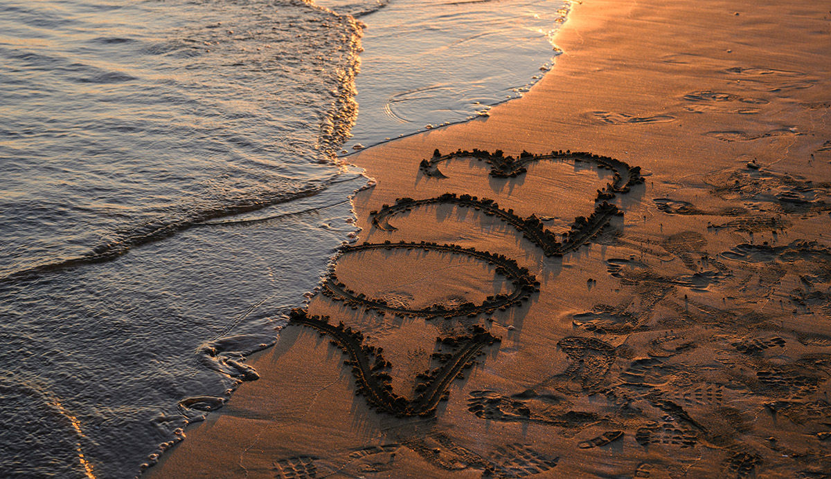 A photo of a beach shore with the year 2023 inscribed in the sand. The water is beginning to wash the inscription away.